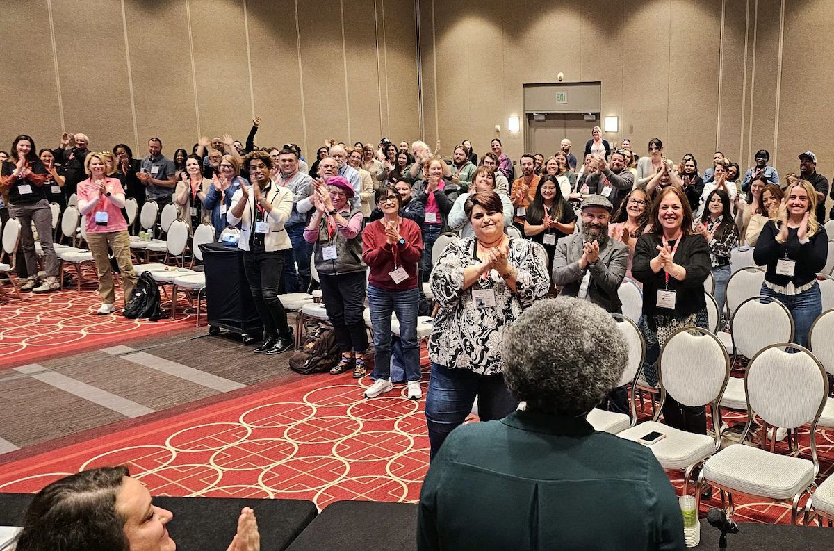 Image of a room giving a standing ovation to a presenter