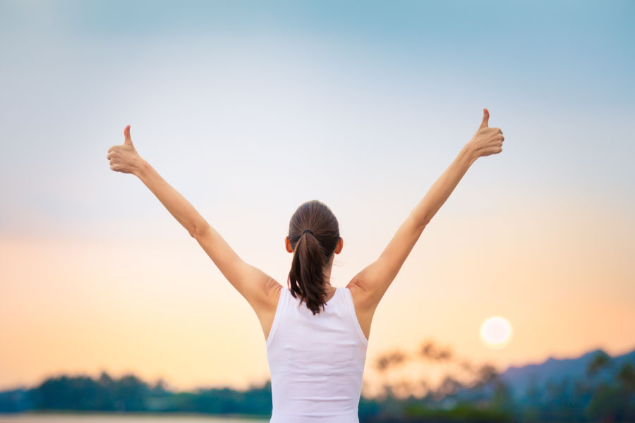 Women raises her hands high and gives thumbs up.