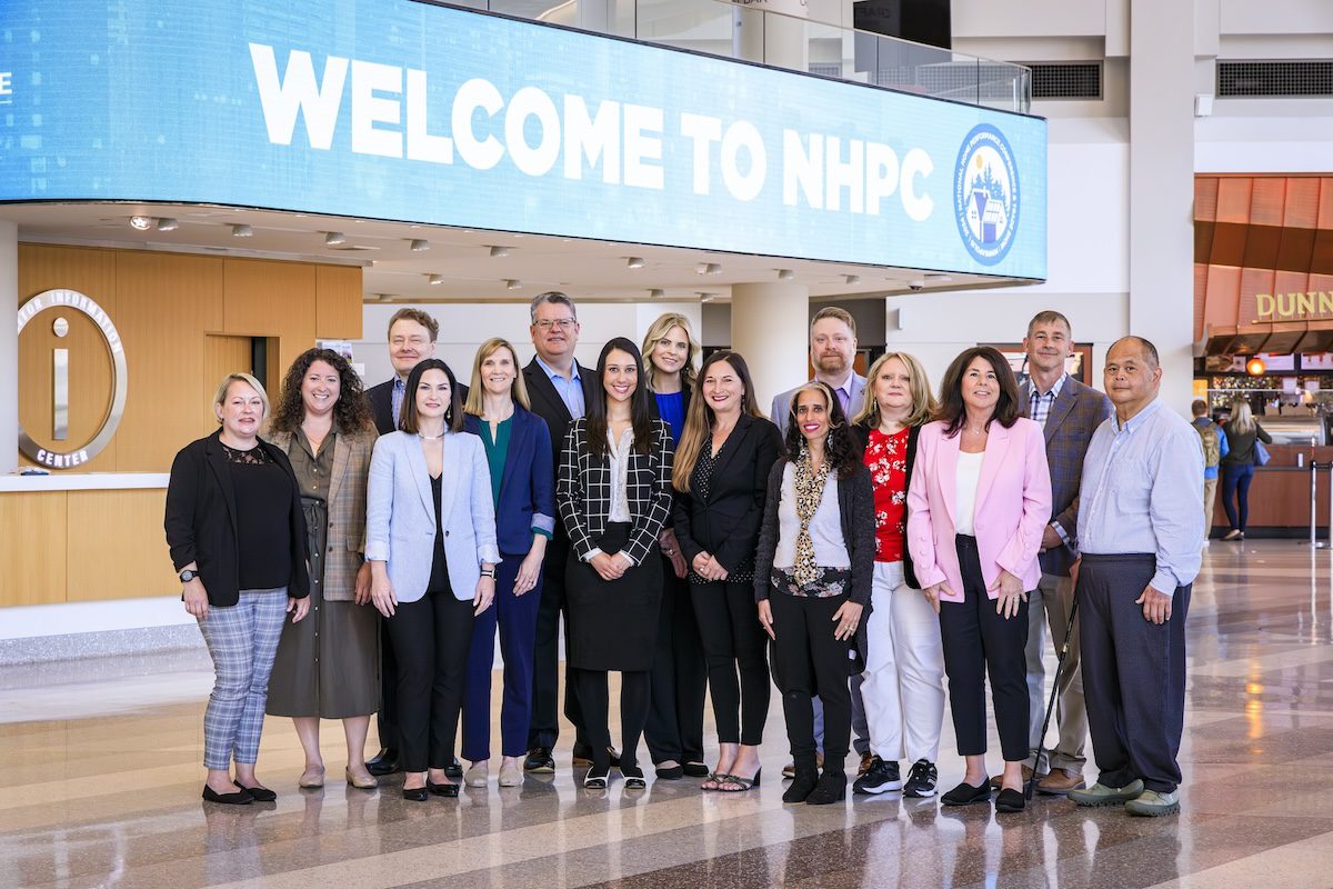 Image of a diverse group of people posing under a banner that says Welcome to NHPC