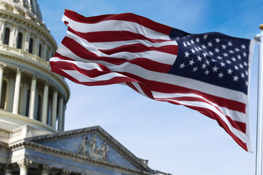 American flag in front of the Capitol building waves in the wind.