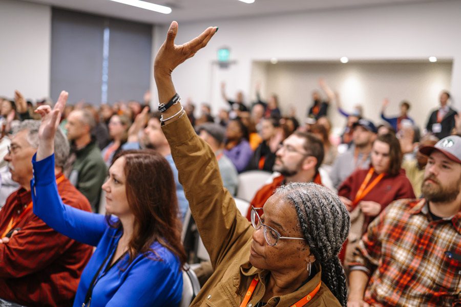 Attendees of NHP'23 raise their hands during a presentation