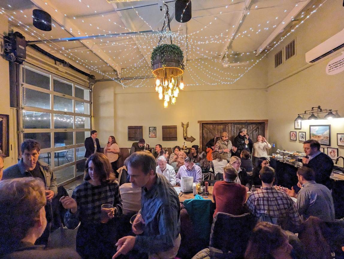 Image of a party with food while people gather and converse