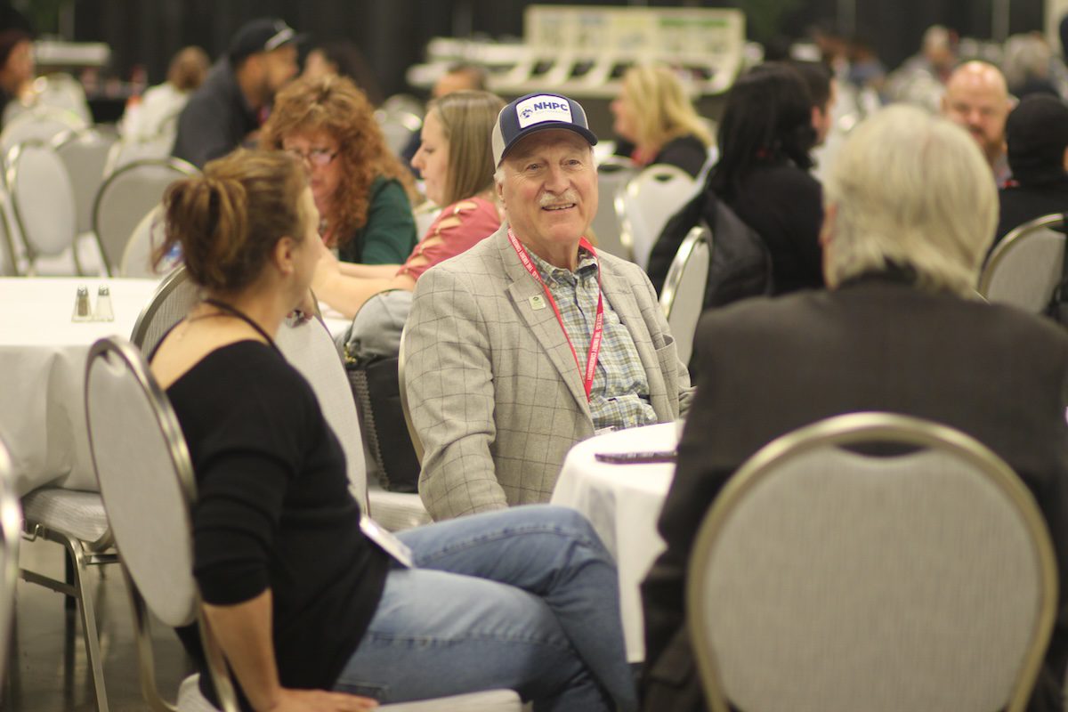 Image of a man smiling while sitting at a table with others