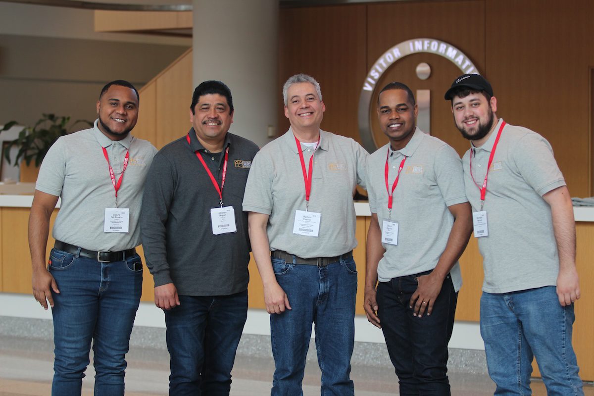 Image of 5 diverse people posing together with red lanyards