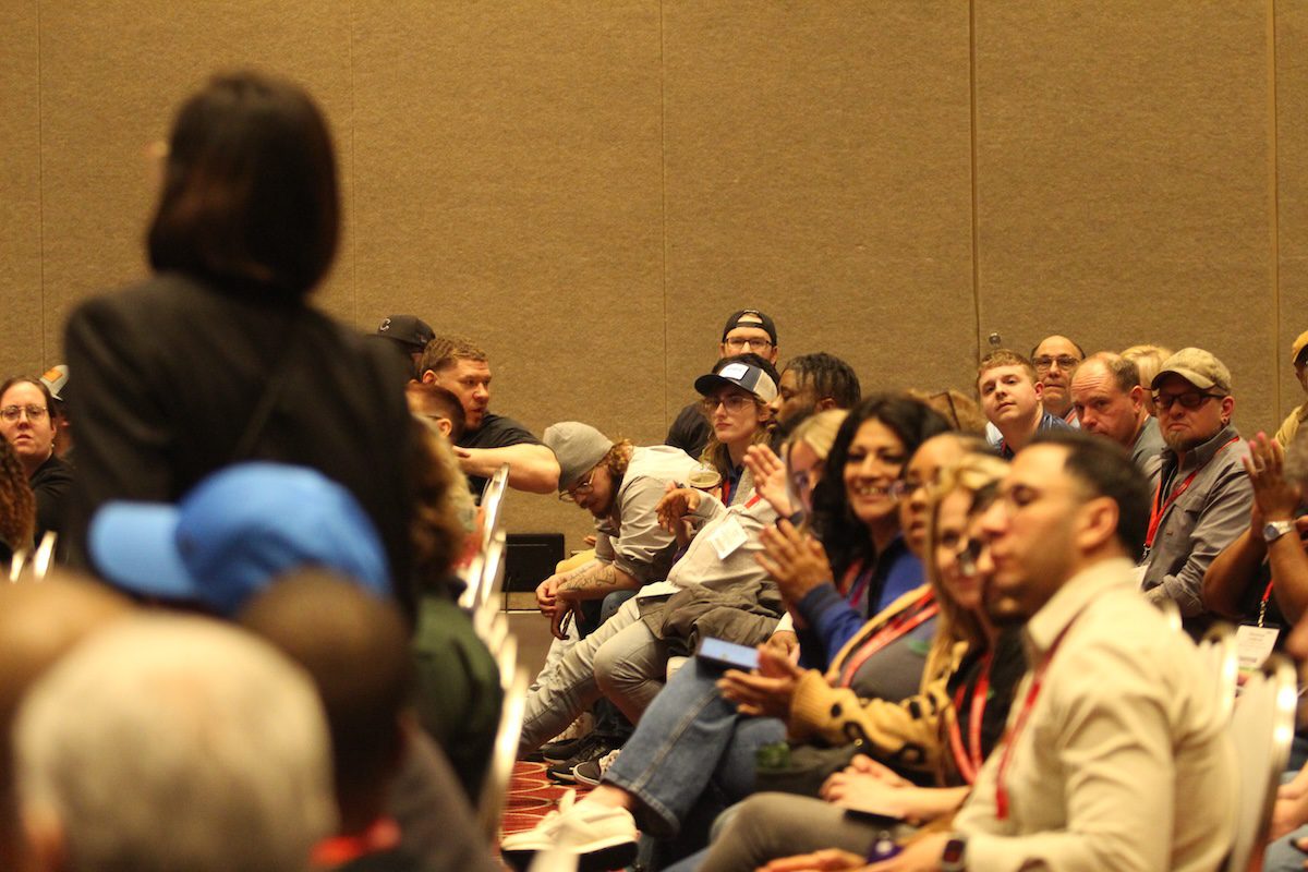 Image of a row of people listening to a speaker and clapping