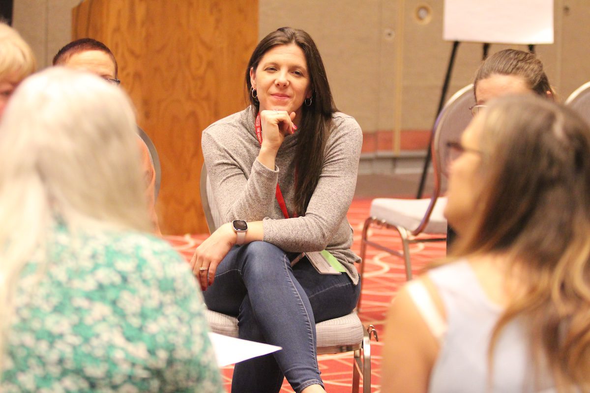 Image of a woman smiling while listening to a group share in a circle