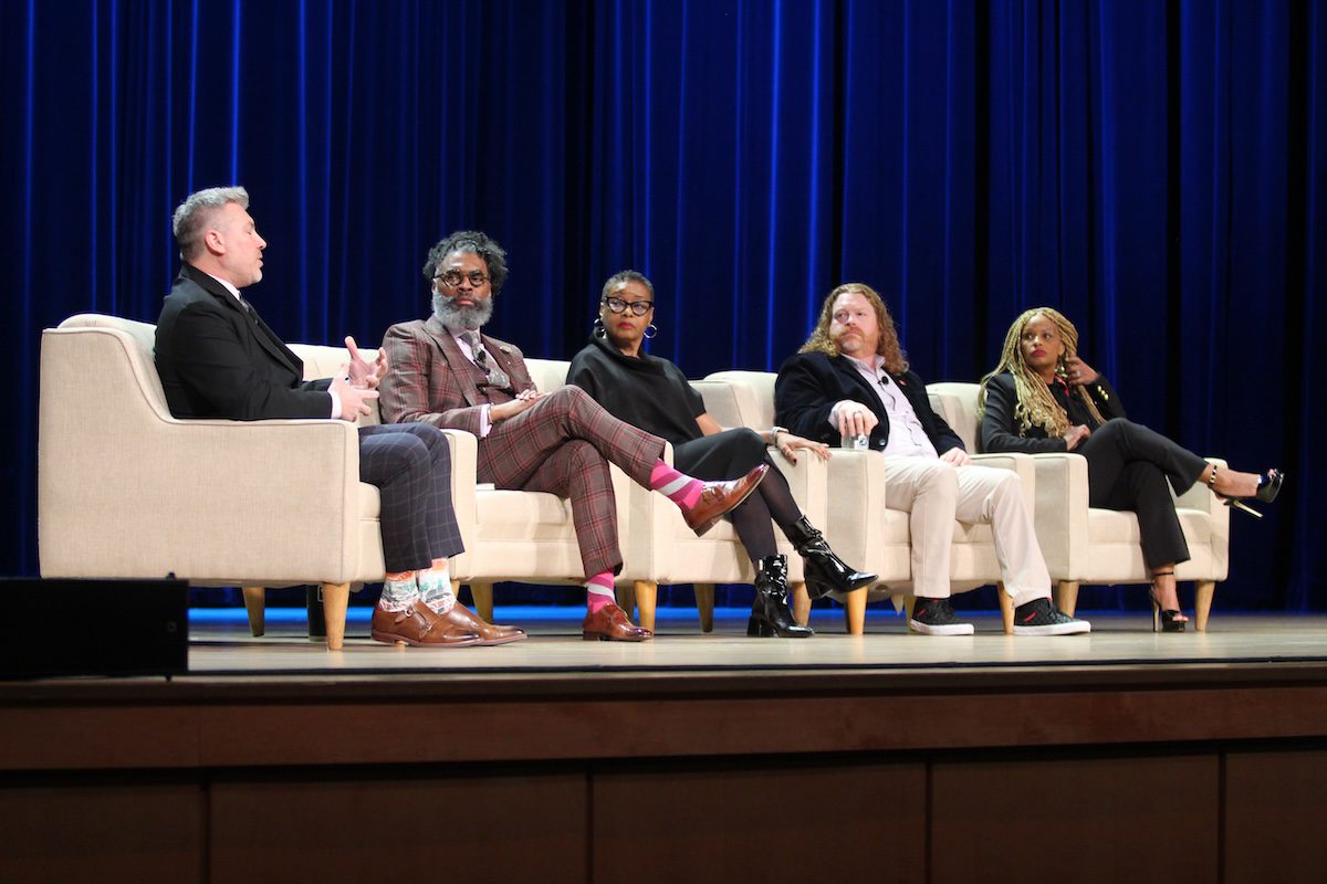 Image of 5 diverse people sharing on stage while sitting in chairs