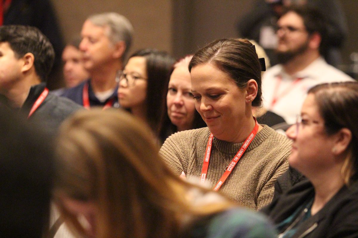 Image of a woman smiling and listening to a speaker