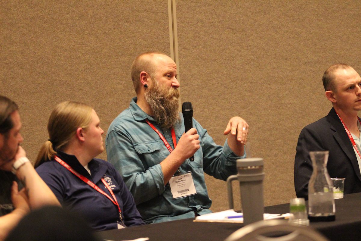 Image of a man speaking on a panel into a microphone