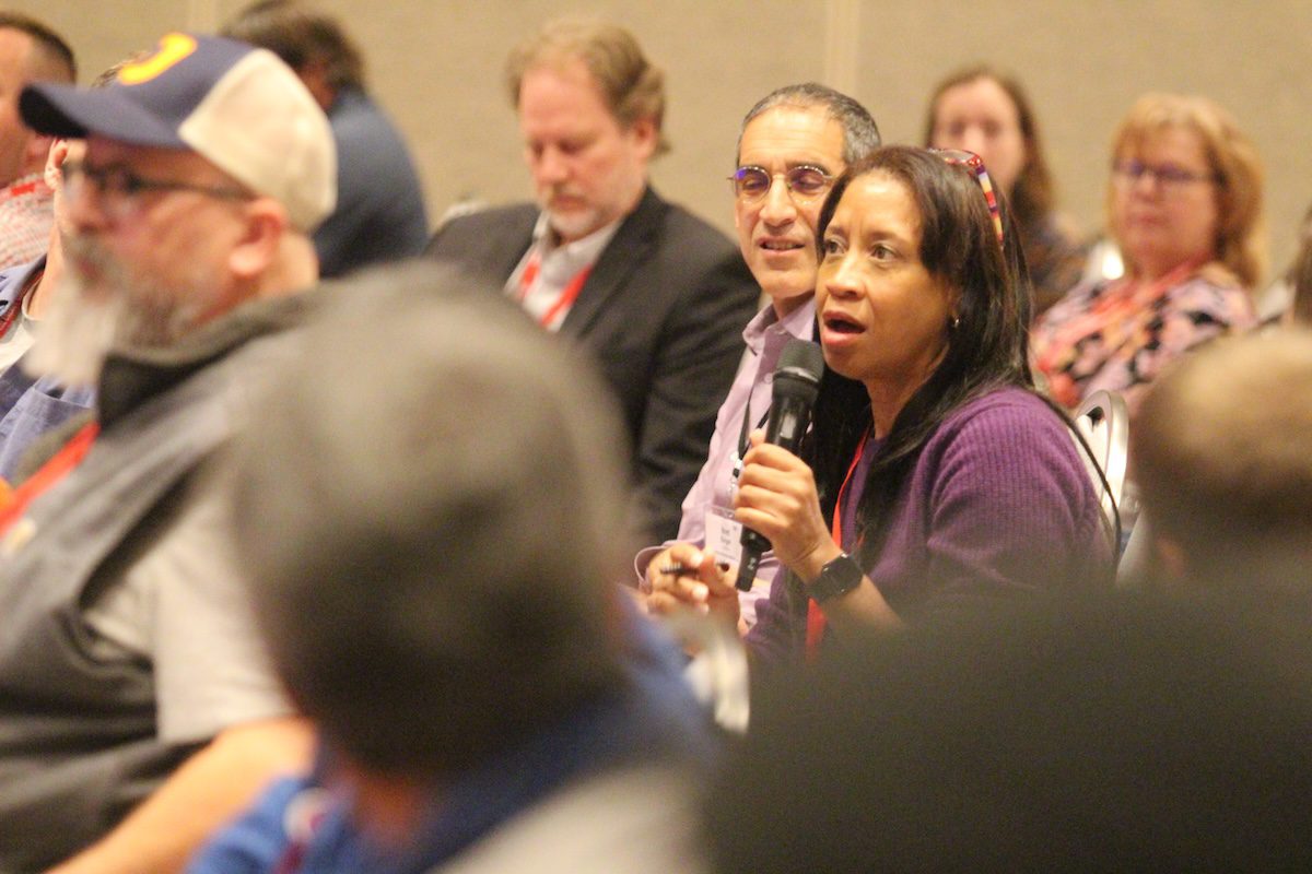 Image of a woman speaking large-group into a microphone