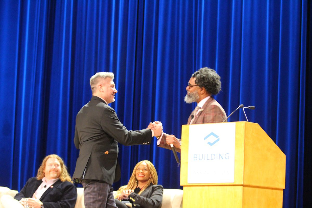 Image of two men shaking hans next to a podium on stage