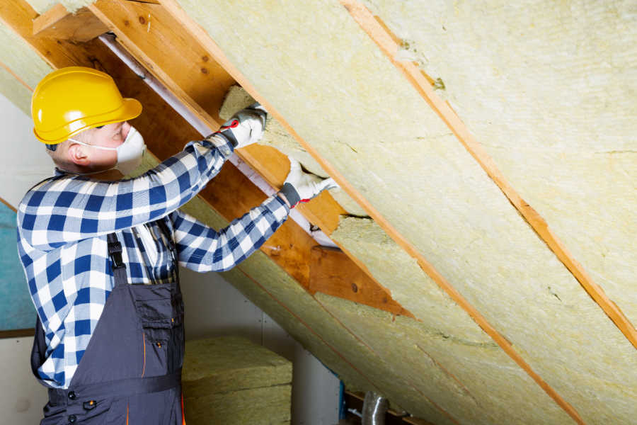 Man installing thermal roof insulation layer - using mineral wool panels. Attic renovation and insulation concept