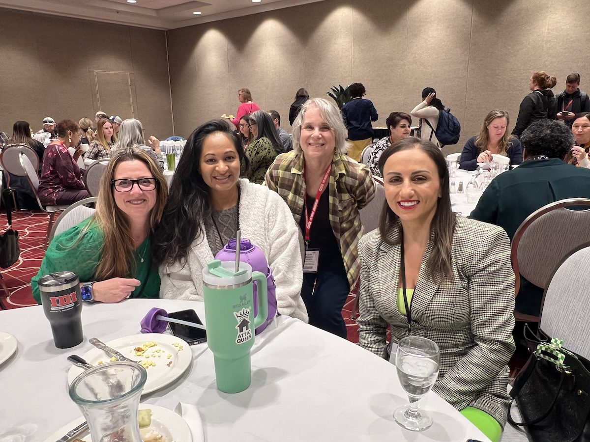 Image of 4 women posing together while having a meal