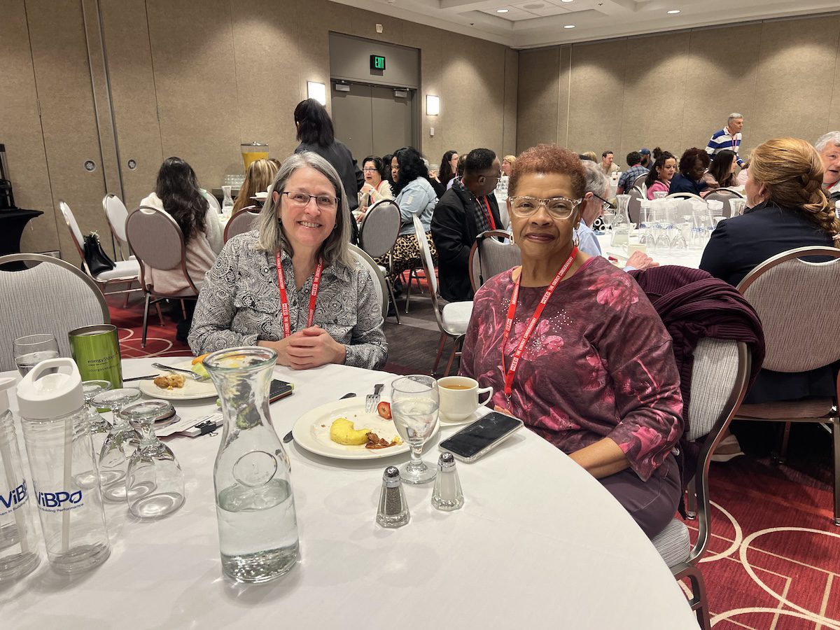 Image of 2 women posing together while having a meal