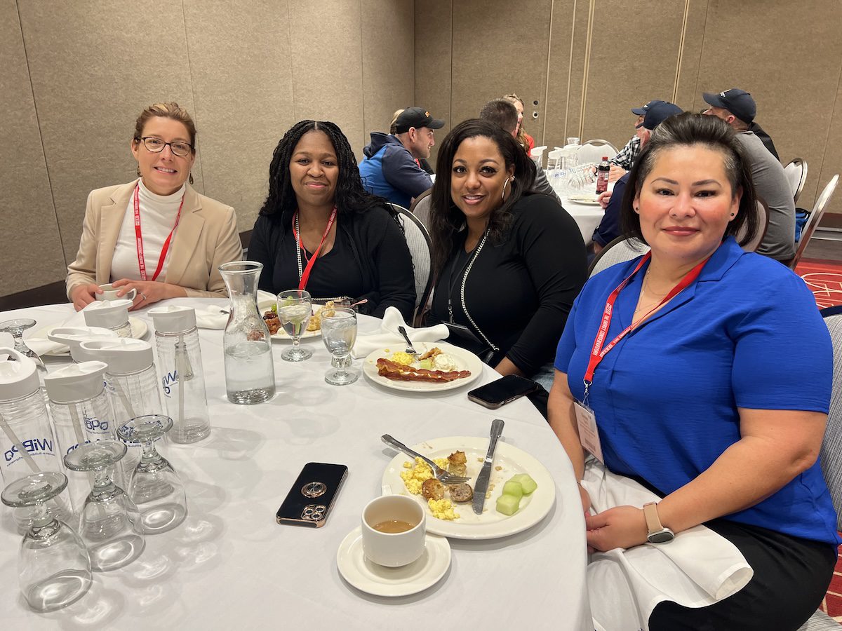 Image of 4 women posing together while having a meal