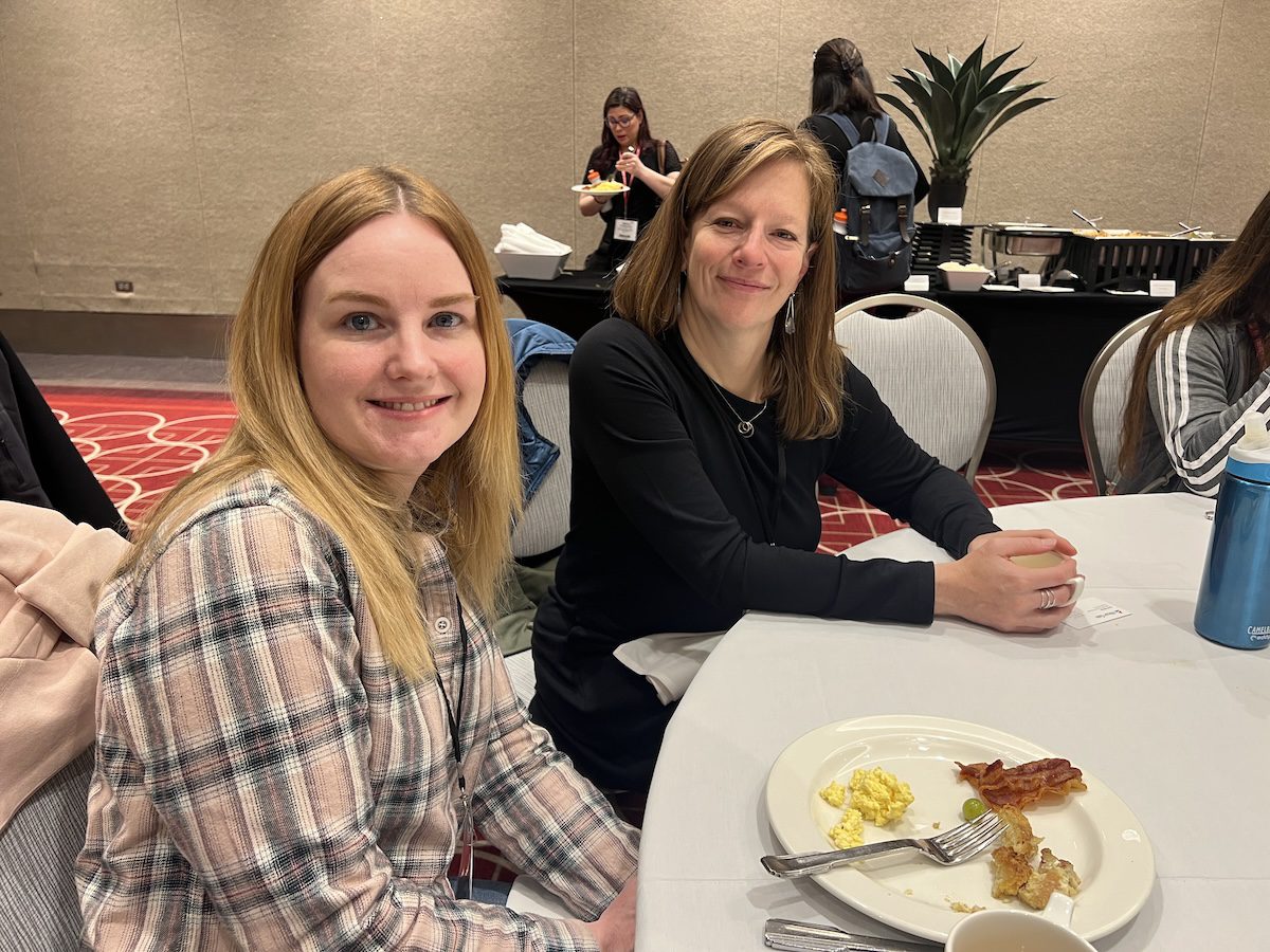 Image of 2 women posing together while having a meal