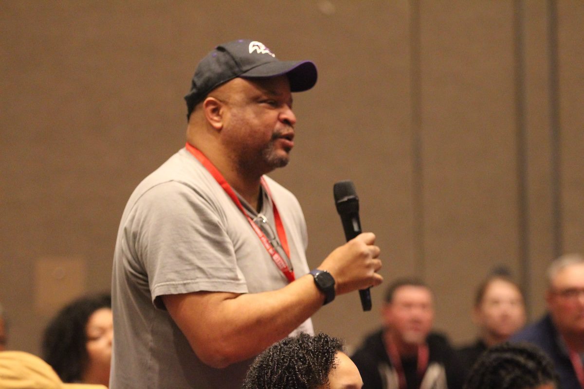 Image of a man asking a question to a speaker into a microphone