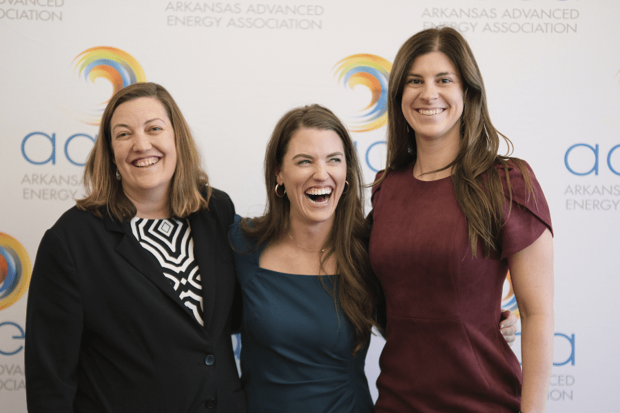 Three women standing against a photo backdrop smiling