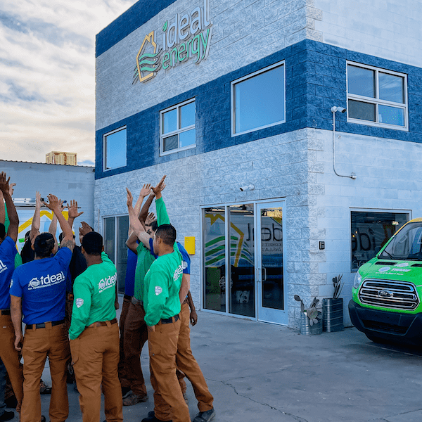 Group of home performance workers standing in a circle with their hands in the air