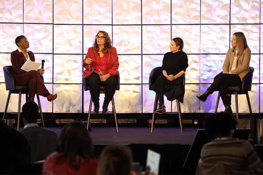 Four women speaking on panel at conference