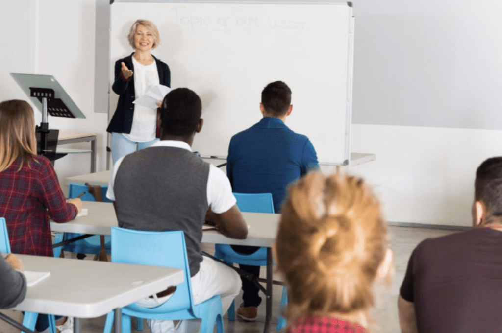 Classroom with teacher at the front and students seen from the back.