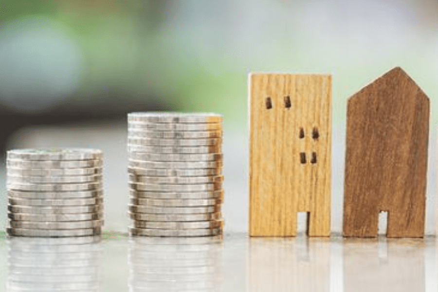 Stacks of coins next to wooden block houses