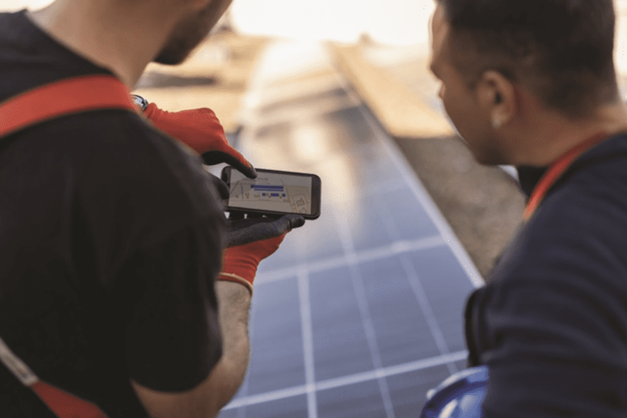 Using a smartphone allows two solar technicians to examine a diagram. (Credit: Jose Carlos Cerdeno)